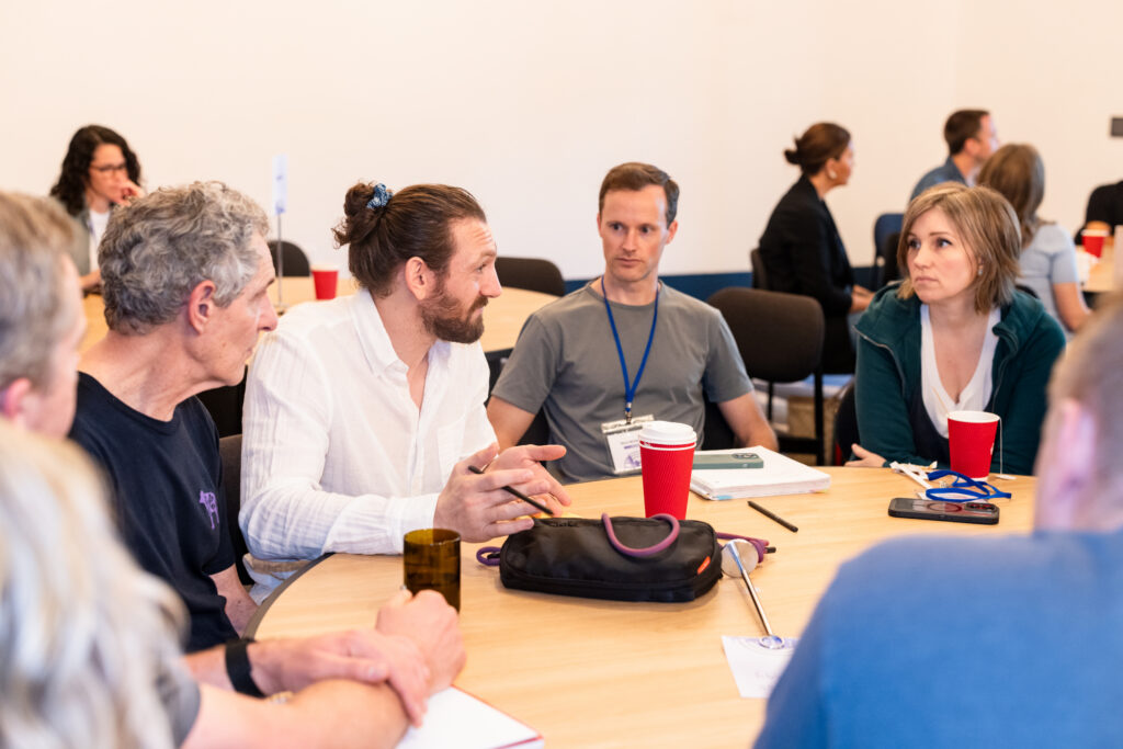 Diverse group of people in a workshop discussing ideas around a table.