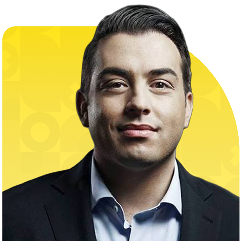 Portrait of a man in a suit against a yellow background with geometric patterns.