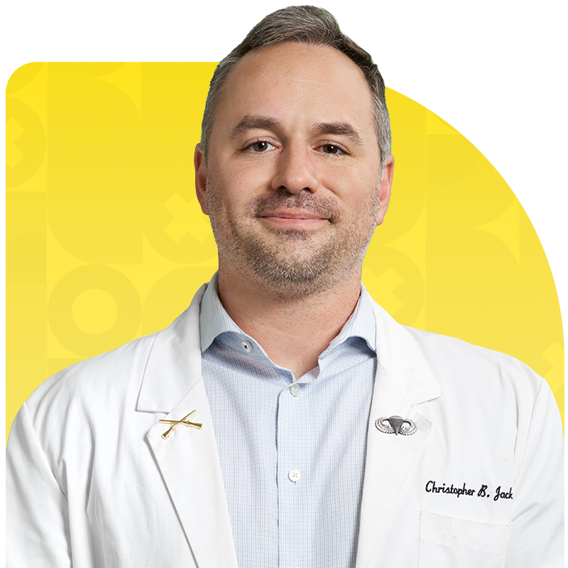 Dr. Christopher B. Jack in a white lab coat with military pins.