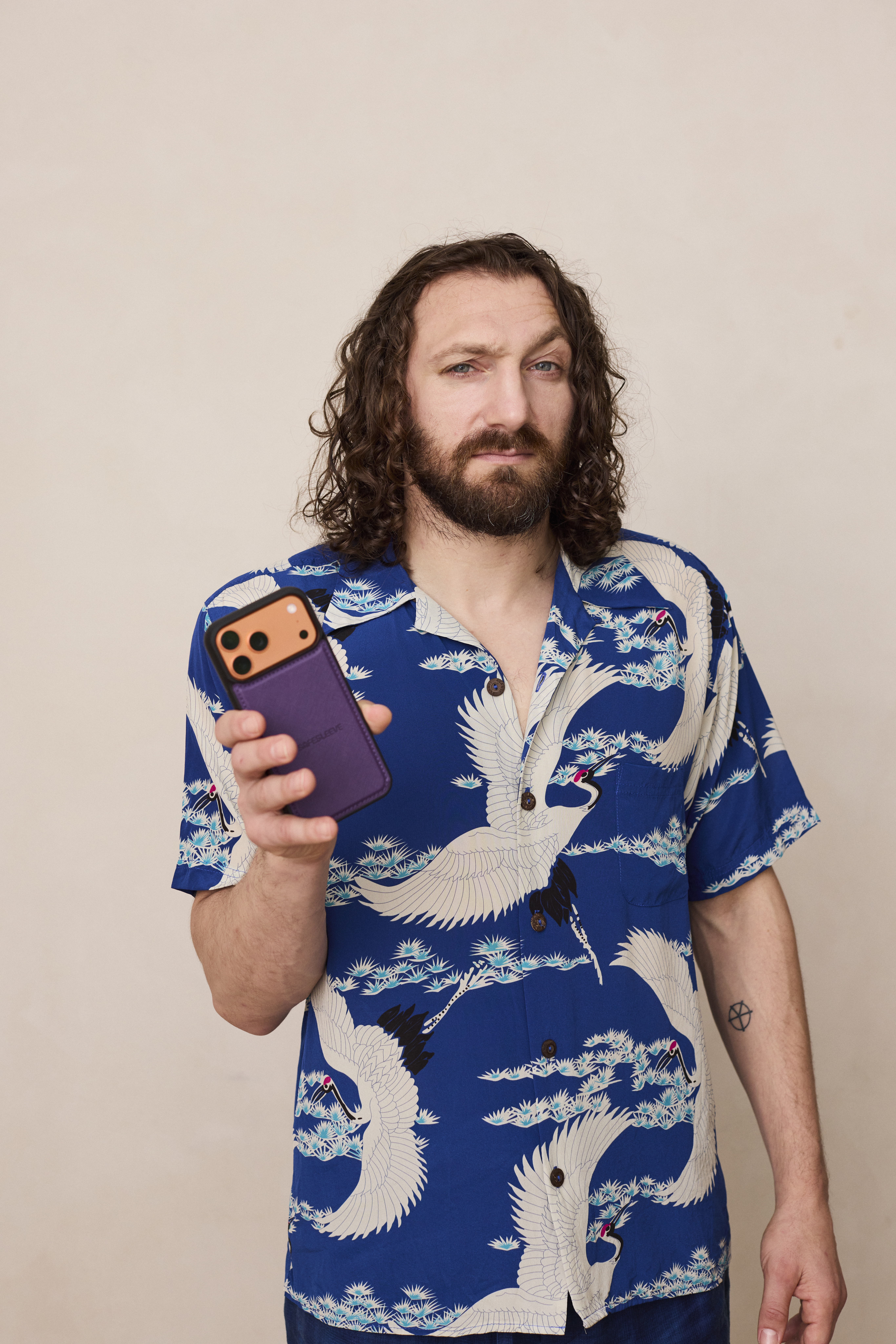 Man in Hawaiian shirt holding a smartphone with a purple case