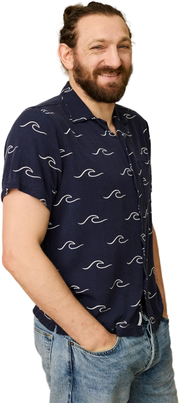 Man with beard wearing a navy wave-patterned shirt and jeans